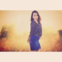 Portrait of smiling young woman standing against wall