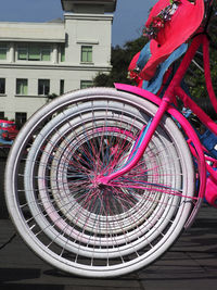 Close-up of bicycle wheel by building in city