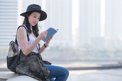 Young woman sitting in park with city in background