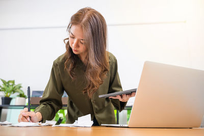 Young woman using laptop while sitting at office