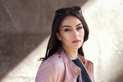 Portrait of young woman standing against wall