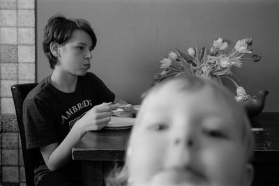 Portrait of boy sitting on table at home