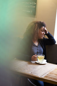 Smiling woman having tea while sitting at restaurant