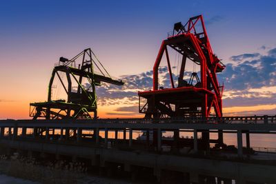 View of cranes against sky at sunset