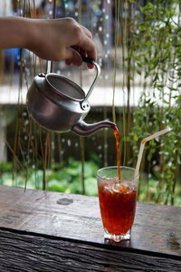 Close-up of hand pouring drink in glass