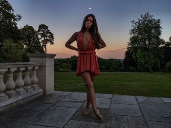Sensuous woman standing on tiled floor by railing during sunset