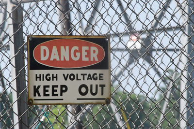 Close-up of warning sign on chainlink fence