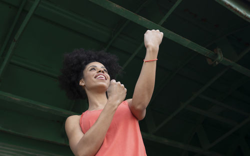 Afro woman making boxing gesture under iron shed