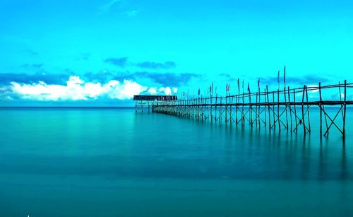 Pier over sea against blue sky
