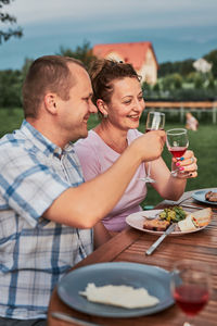 Smiling couple toasting wine glass sitting outdoors