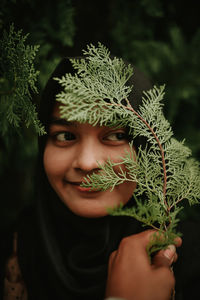 Portrait of young woman holding plant