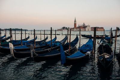 Gondolas moored on sea during sunset