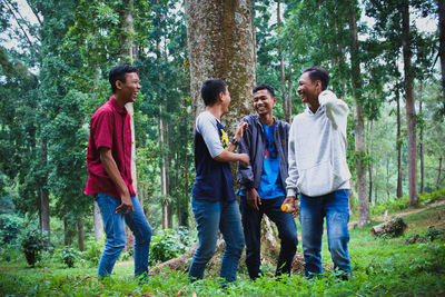 Happy friends talking against trees in forest