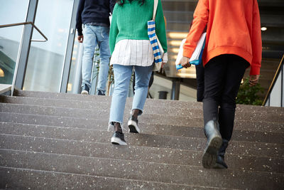 Low section of friends walking up of steps in university