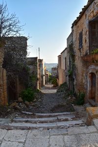 Footpath amidst buildings against clear sky