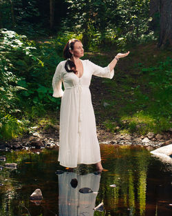 Portrait of smiling young woman standing by lake