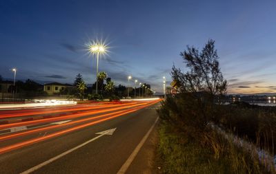 Light trails on road against sky at night