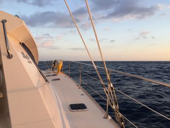 Sailboat sailing in sea against sky during sunset