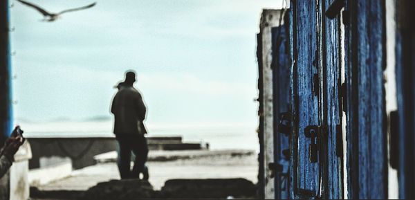 Rear view of silhouette man standing against sky