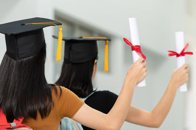 Rear view of women holding certificate