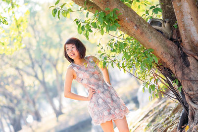 Young woman standing against tree