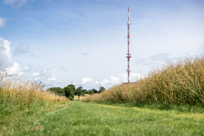 Scenic view of field by communications tower against sky