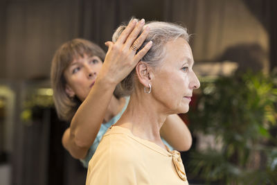 Woman helping senior woman with her hair in a shop