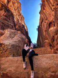 Full length of woman sitting on rock