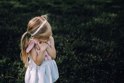 High angle view of girl embracing stuffed toy while standing on grass