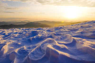 Aerial view of snowcapped mountains against sky during sunset