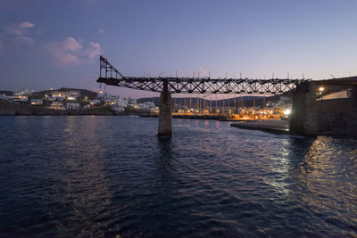 Illuminated bridge over river against sky at night