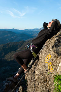 Concept: adventure. climber woman with helmet and harness. lying on a rock taking a sunbath. via ferrata in the mountains.