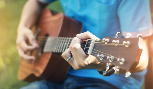 Midsection of man playing guitar