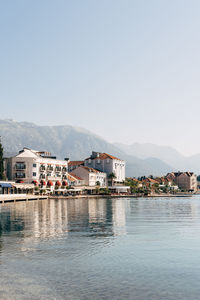 Buildings by river against clear sky