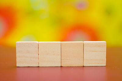 Close-up of wooden blocks on table against multi colored background