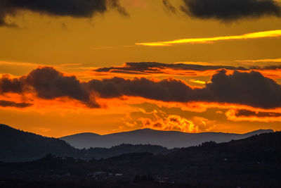 Scenic view of silhouette mountains against romantic sky at sunset