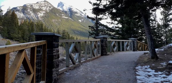 Railing by snowcapped mountain against sky