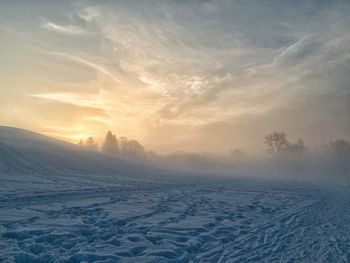 Scenic view of snow covered landscape against sky during sunset