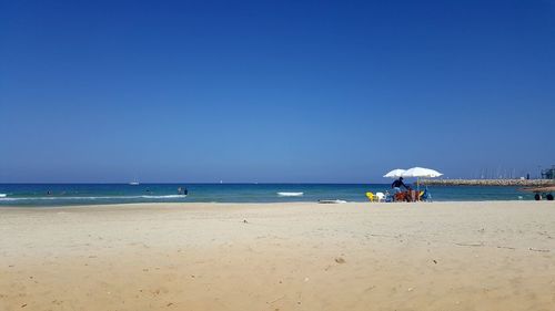 Scenic view of beach against clear blue sky