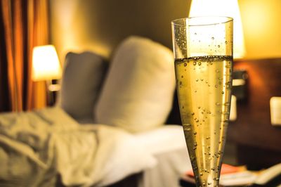 Close-up of champagne glass in illuminated hotel room