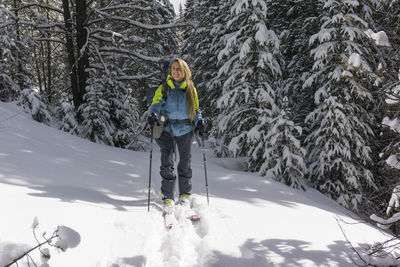 Smiling young female hiker splitboarding on snow covered mountain