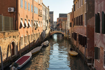 Canal amidst buildings in city against sky