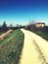 View of empty road on field against clear blue sky