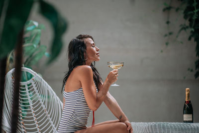 Full length of a young woman drinking glass