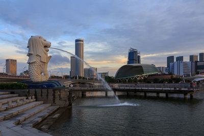 Buildings at waterfront against cloudy sky