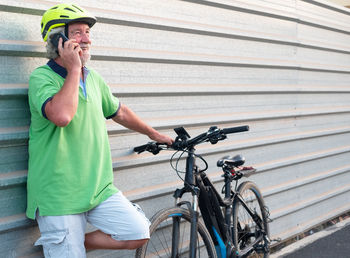 Smiling senior man talking on mobile phone while standing by bicycle