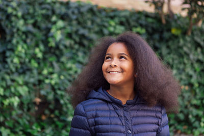 Portrait of smiling young woman standing against plants