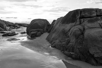 Rock formations on beach against sky