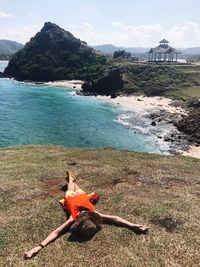 High angle view of woman lying on cliff against sea