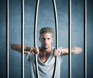 Portrait of young man standing against metal grate